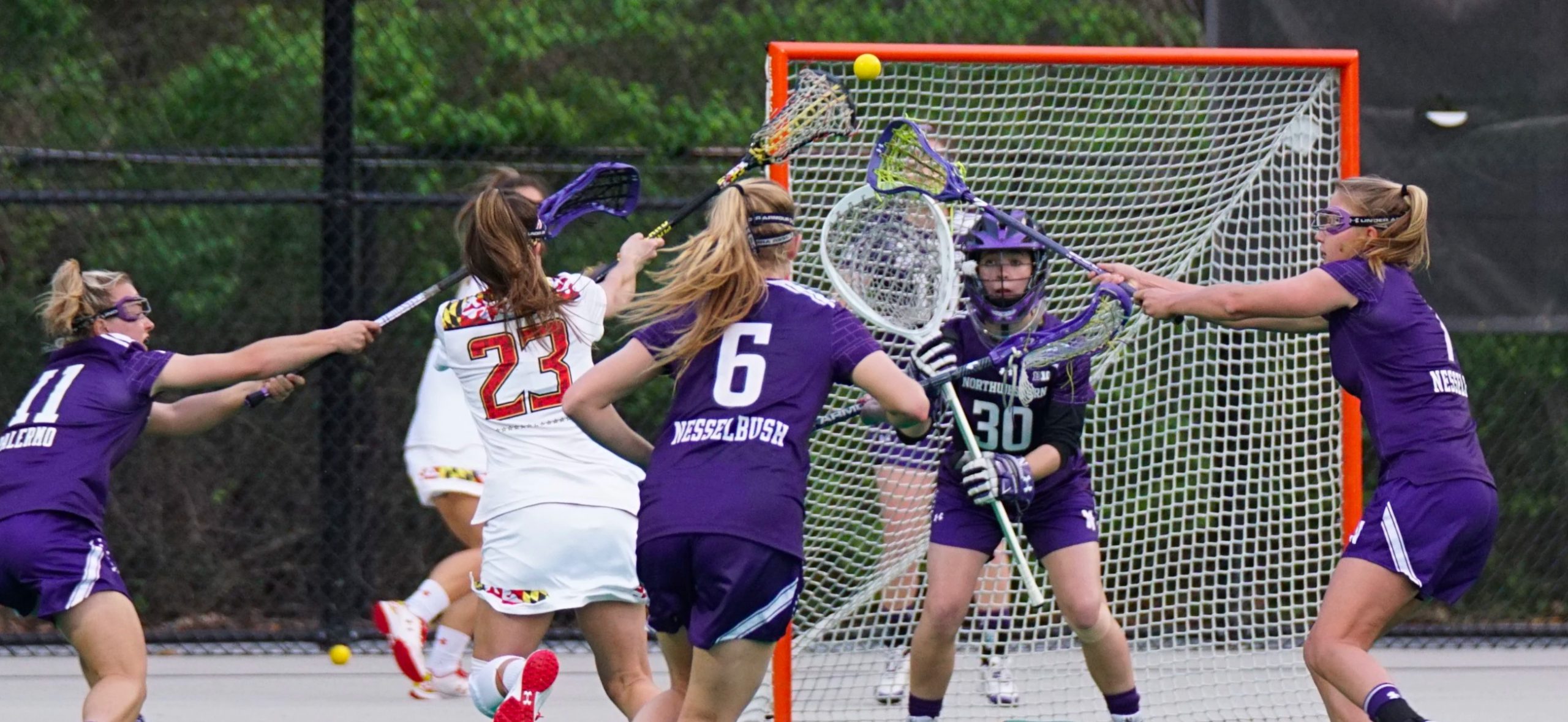 Women's Field Lacrosse players, one shooting on net