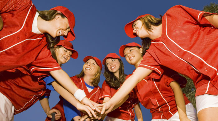 softball team putting hands in on top of each other during a team huddle